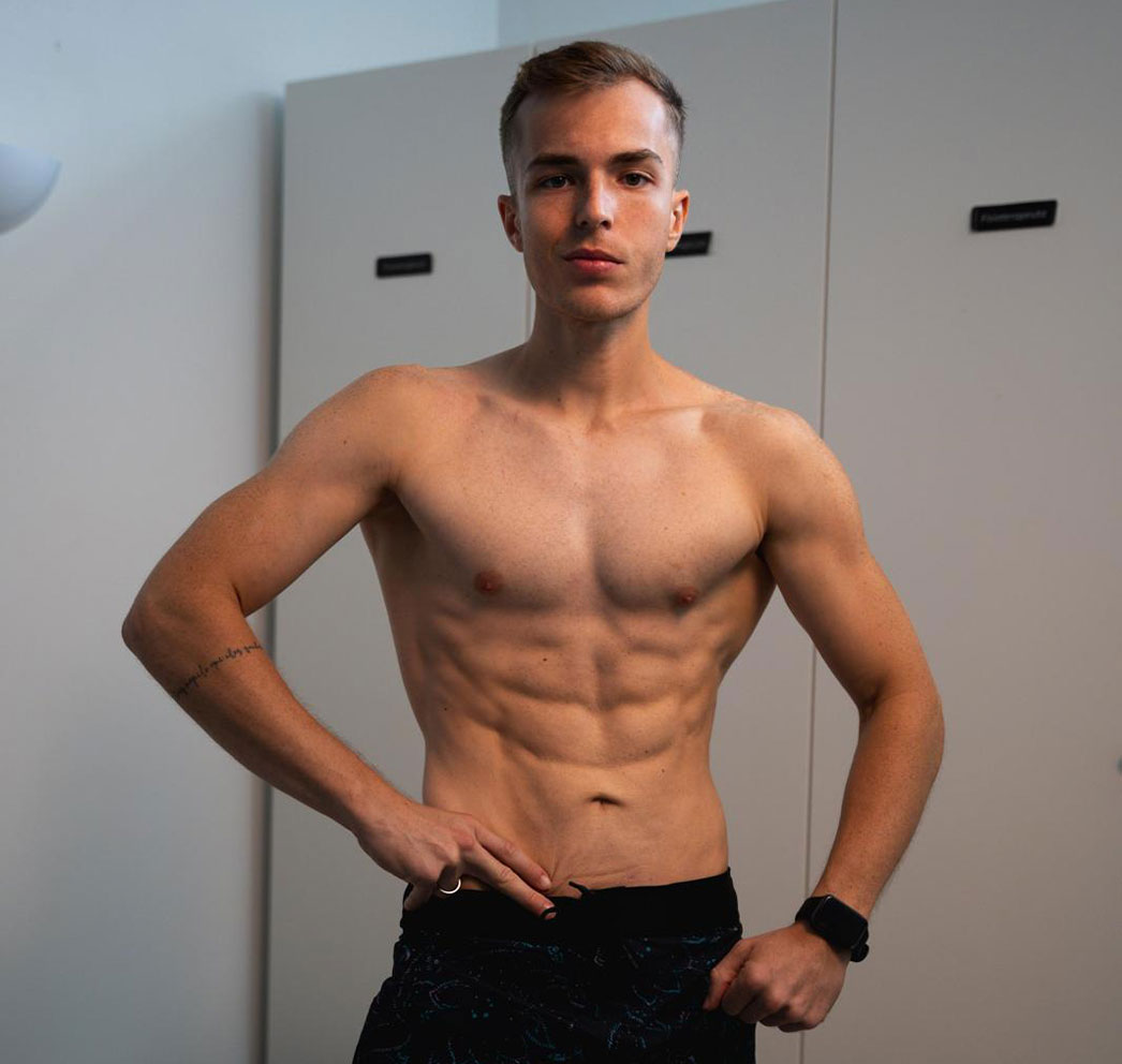 O coach sem camisa com as mãos na cintura num balneário.
